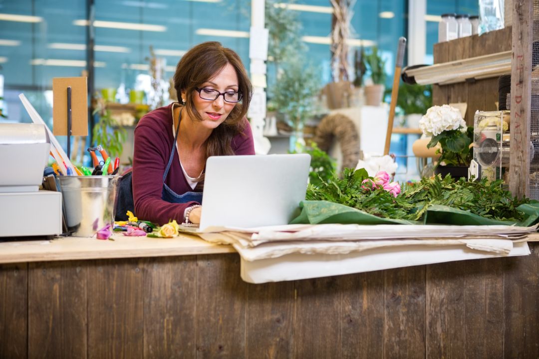 Mid adult female florist using laptop at counter in flower shop