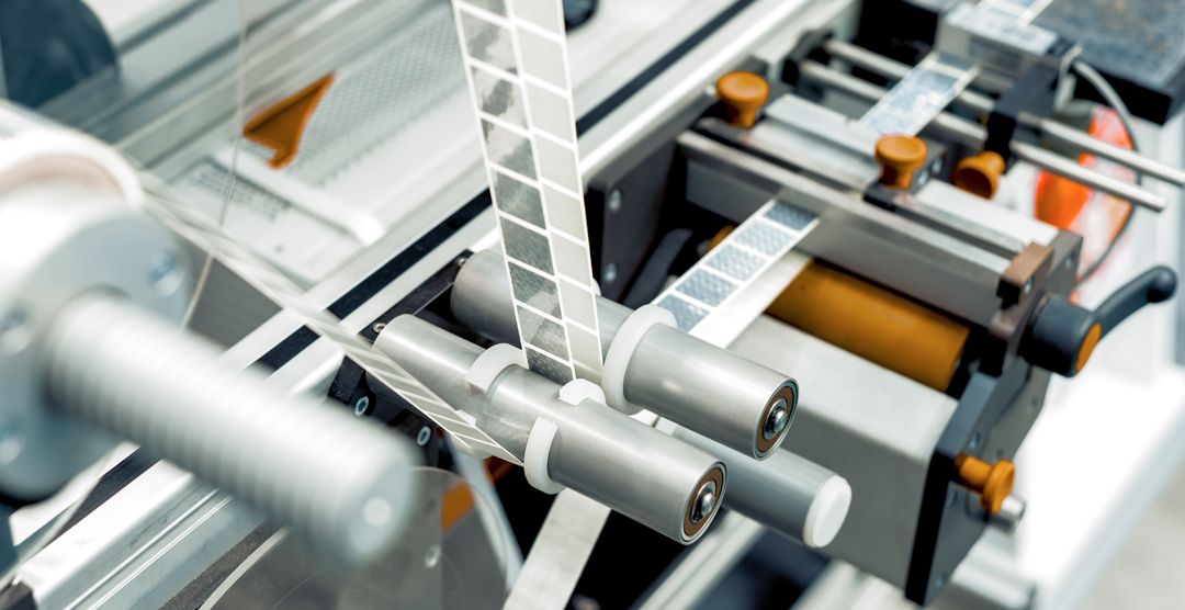 Automatic labeling machine. The labeled tape is located between the feed rollers.