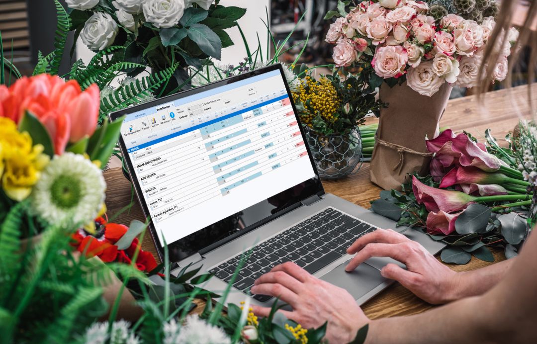 Florist using laptop with blank screen with flowers bouquet